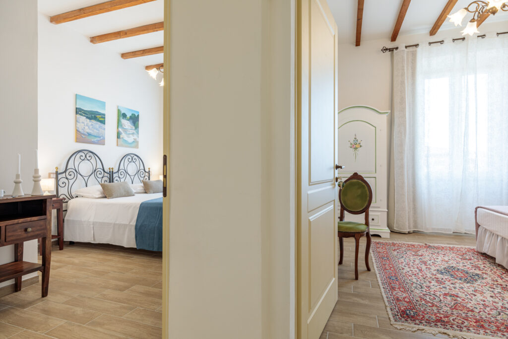 Vista delle camere comunicanti di Villa Fontis Rapolano con letti matrimoniali, arredi in stile toscano, pavimento in gres effetto legno e ambienti luminosi ideali per famiglie e piccoli gruppi