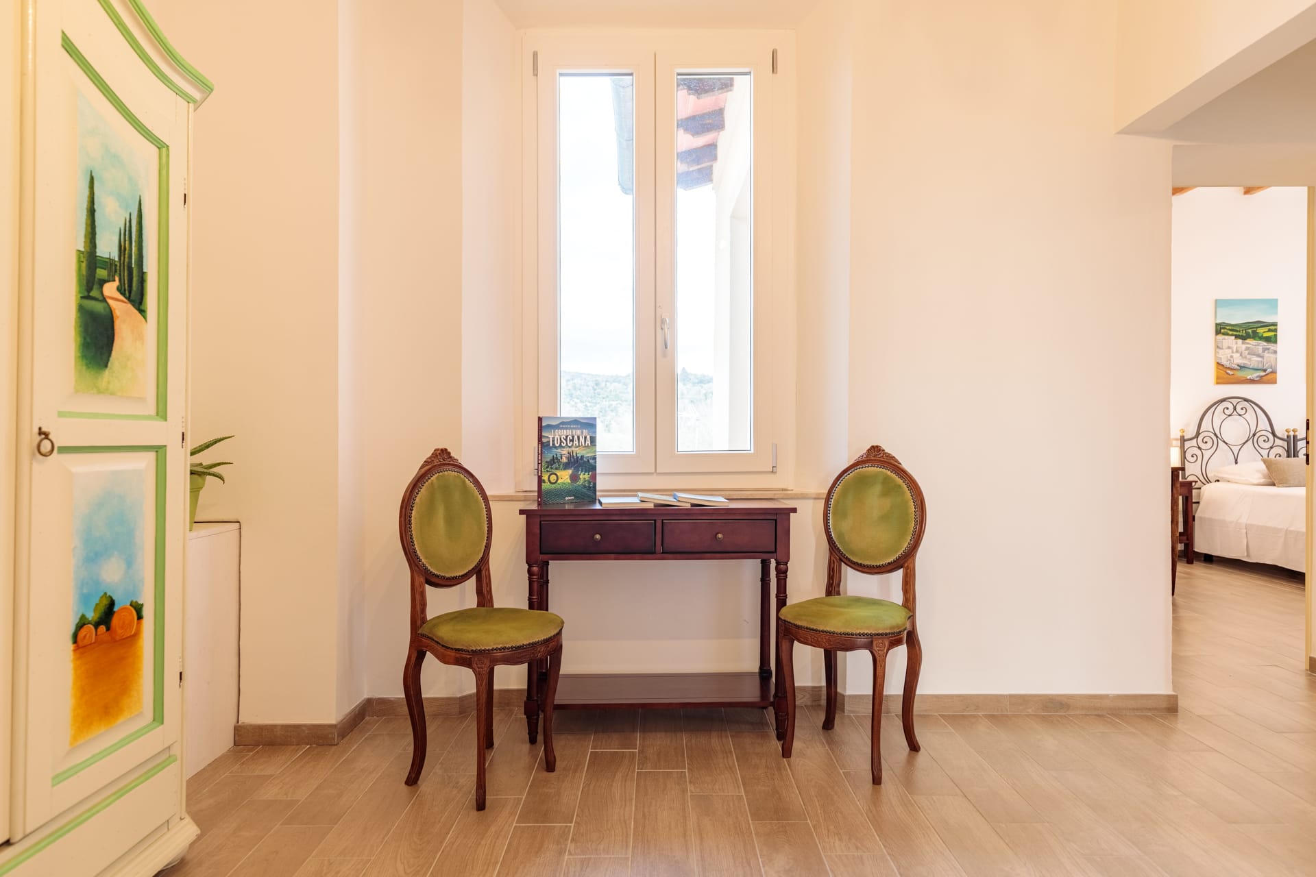 Angolo relax di Villa Fontis Rapolano con scrivania in legno, sedie classiche e finestra panoramica.