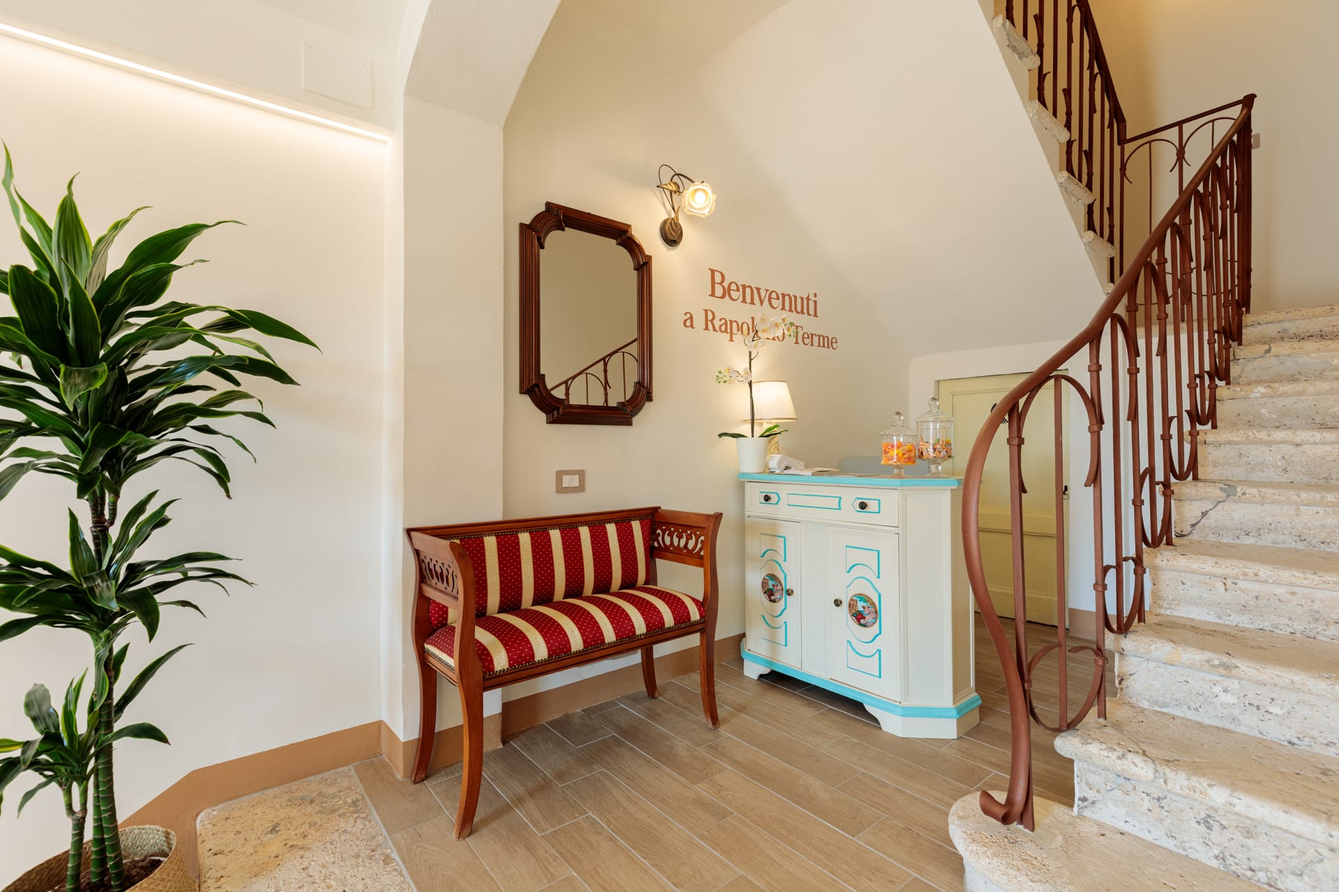 Ingresso interno di Villa Fontis Rapolano con reception accogliente, scala in travertino e arredi storici.