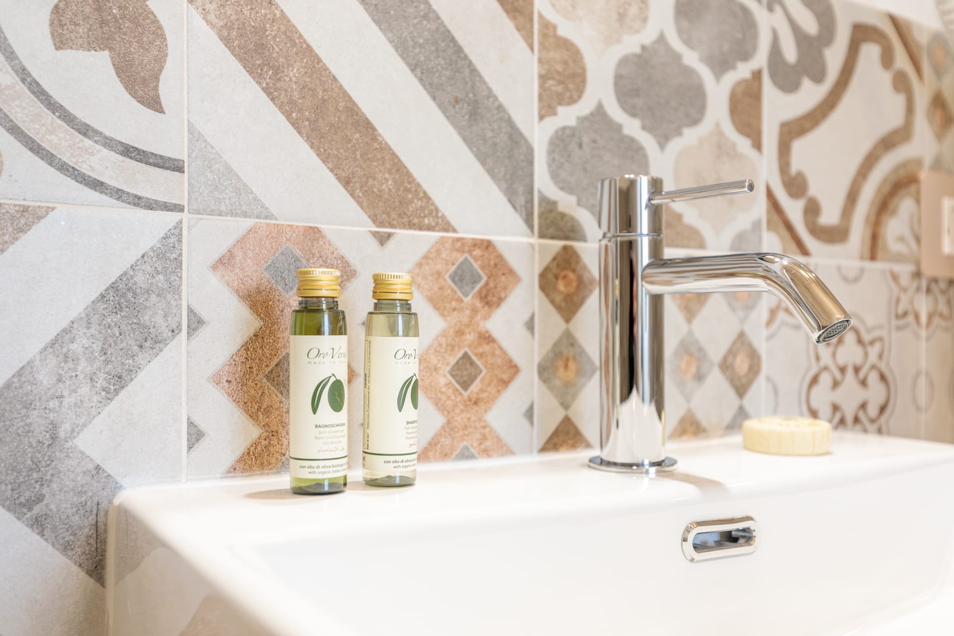 Dettaglio del bagno privato di Villa Fontis Rapolano con lavabo, rivestimenti decorativi e set cortesia.