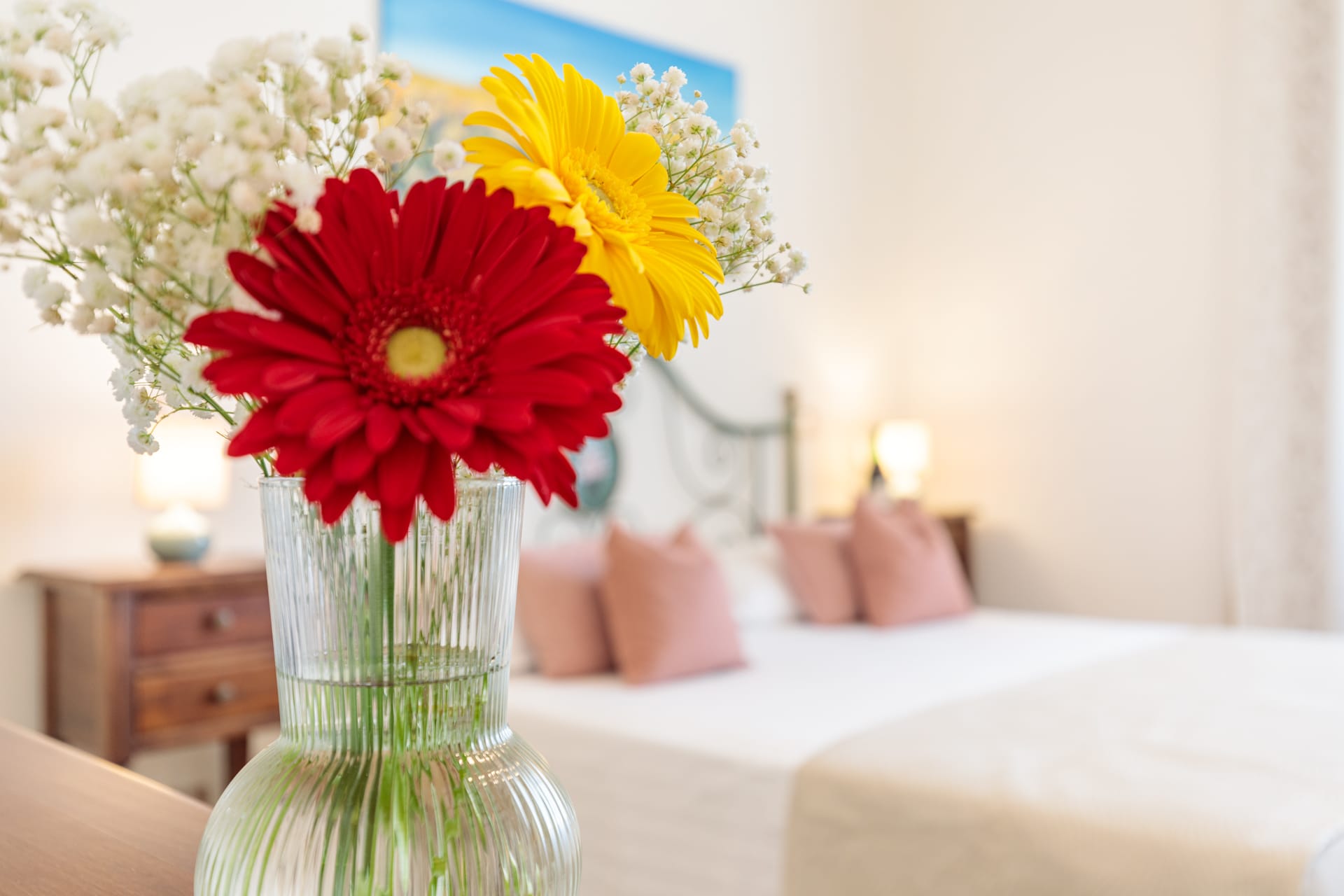 Camera di Villa Fontis Rapolano con fiori freschi in primo piano, letto matrimoniale e atmosfera accogliente.
