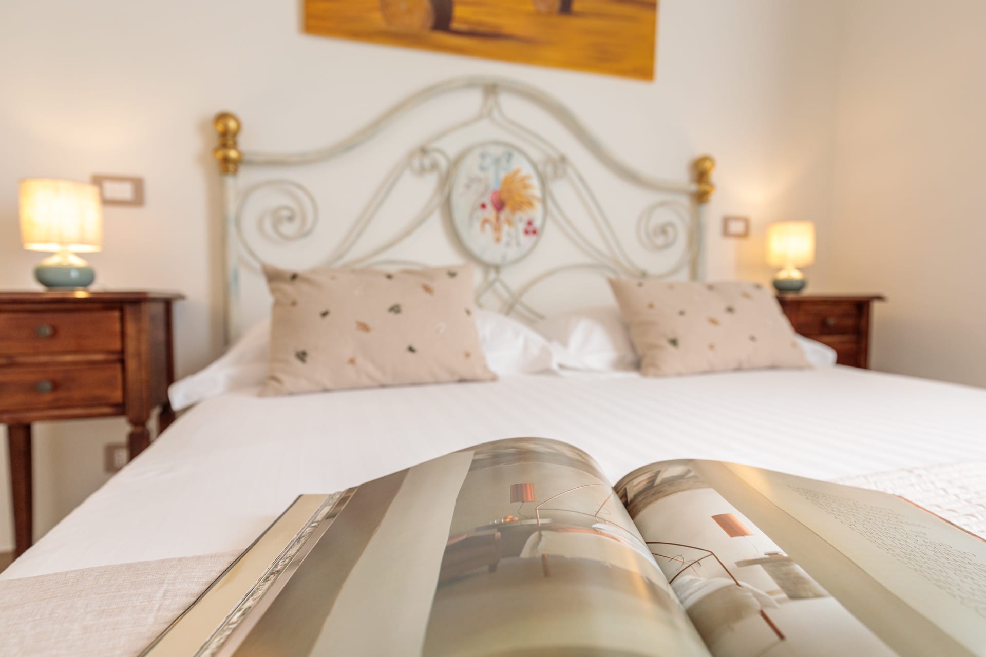 Camera matrimoniale di Villa Fontis Rapolano con letto in ferro battuto, cuscini e arredi eleganti.