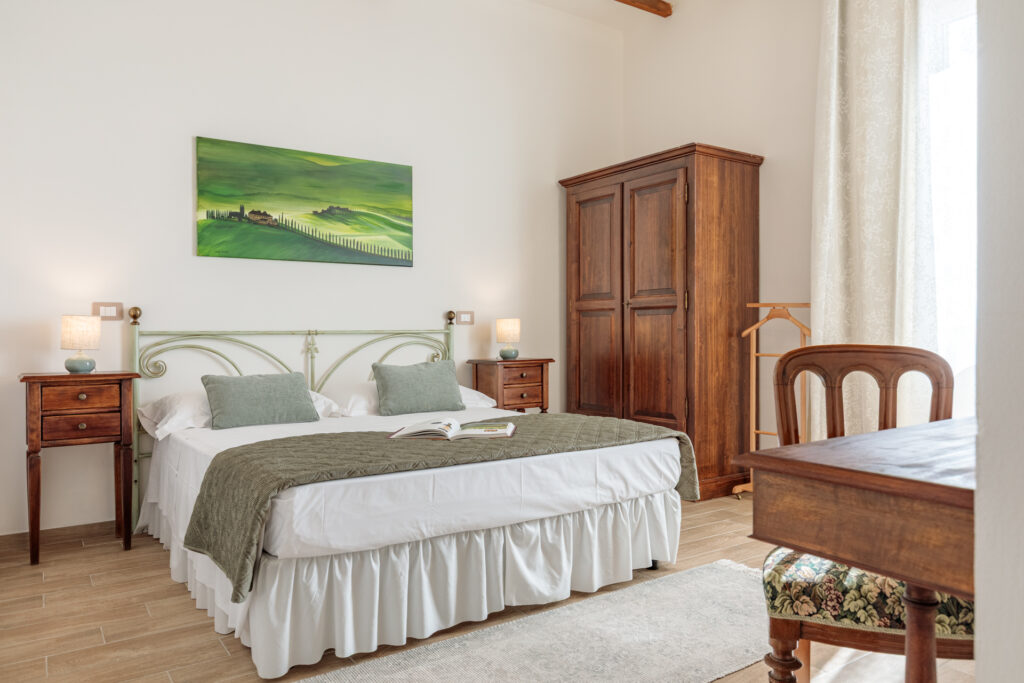 Luminosa camera matrimoniale di Villa Fontis Rapolano con letto king size, armadio in legno massello, comodini, dipinto ispirato alle colline toscane e arredi in stile tradizionale