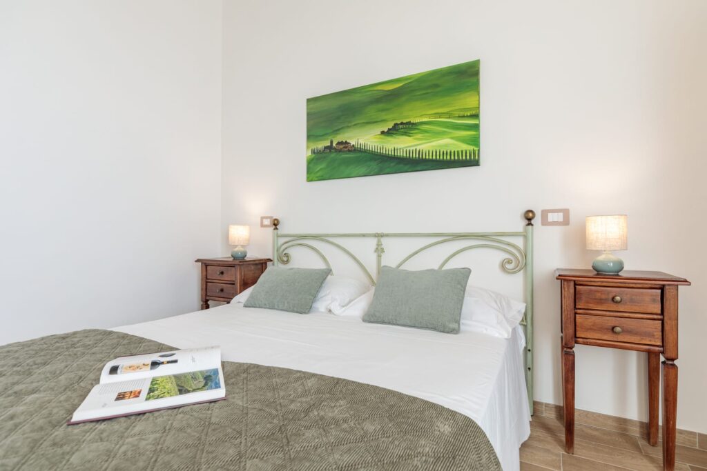 Camera matrimoniale luminosa di Villa Fontis Rapolano con letto matrimoniale, comodini e arredi in stile toscano a Rapolano Terme