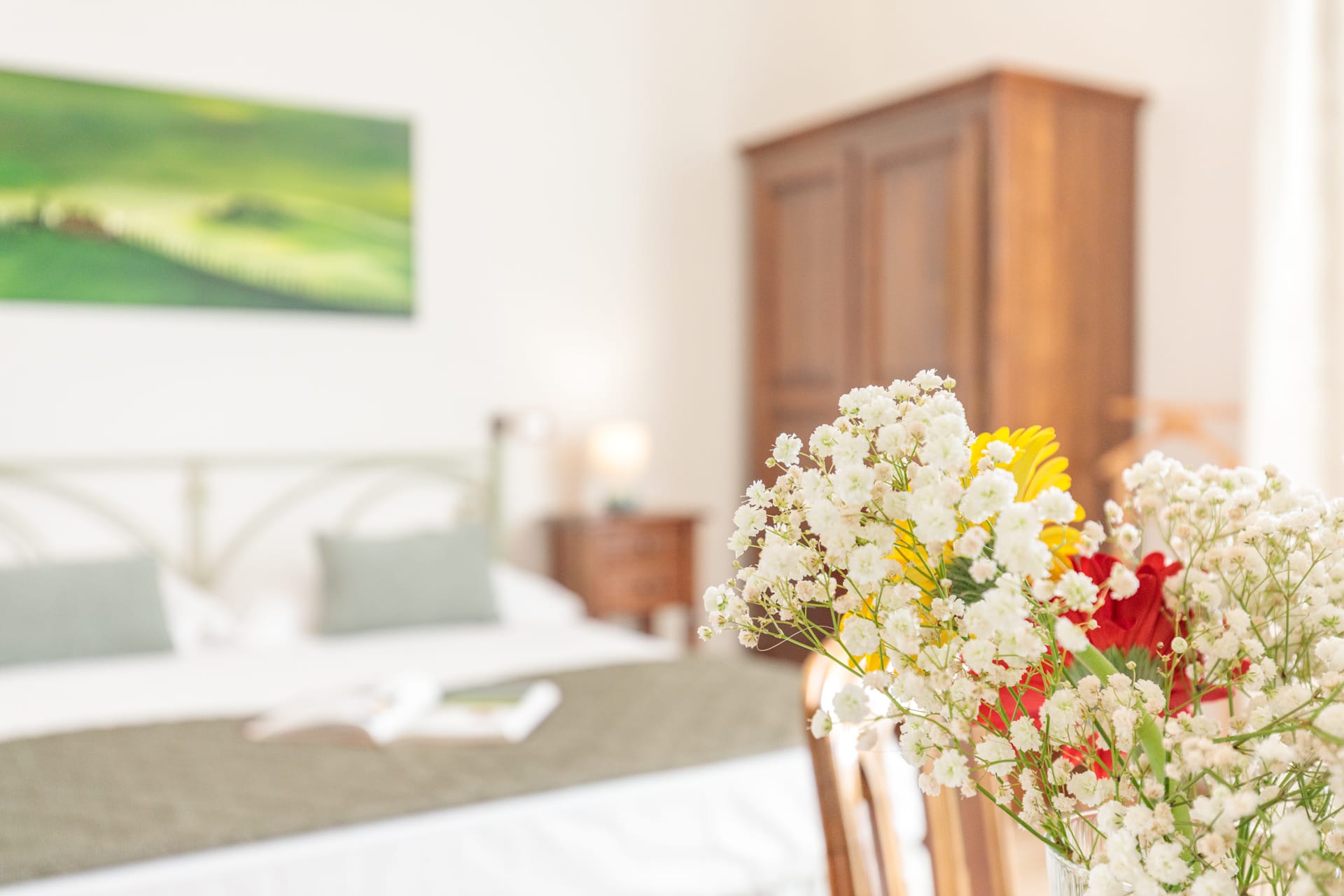 Dettaglio di camera a Villa Fontis Rapolano con fiori freschi, letto matrimoniale e arredi in stile toscano.
