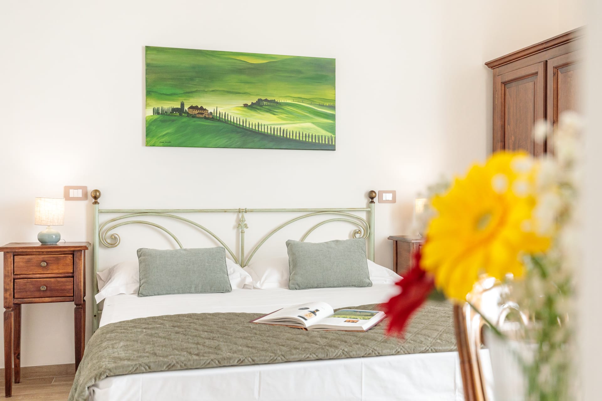 Camera matrimoniale luminosa di Villa Fontis Rapolano con letto, comodini in legno e arredi eleganti.