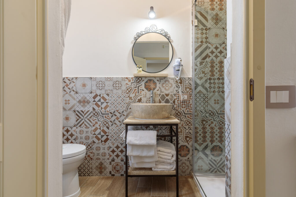 Bagno privato della Camera Matrimoniale con Letti Singoli di Villa Fontis a Rapolano Terme, con doccia, lavabo in pietra e rivestimenti decorati.