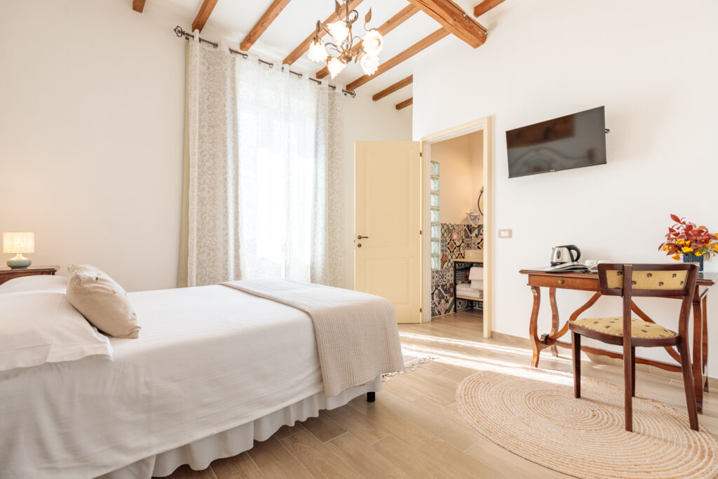 Camera Matrimoniale Deluxe di Villa Fontis Rapolano a Rapolano Terme con letto matrimoniale, bagno privato, TV e angolo relax.