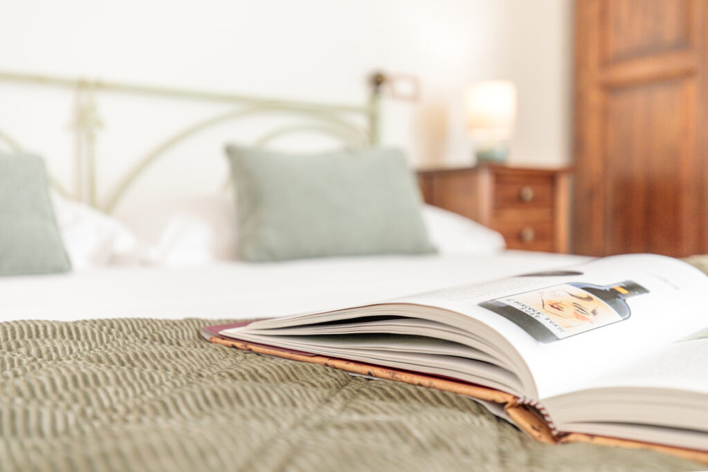 Libro aperto sul letto della Camera Matrimoniale Standard di Villa Fontis Rapolano, ideale per un soggiorno rilassante.